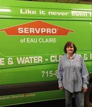 Woman with button down standing in front of green SERVPRO van