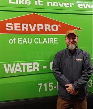 Man in SERVPRO jacket standing in front of a green SERVPRO van