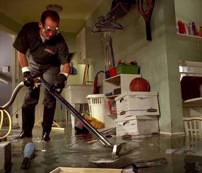 Male employee extracting water from a flooded room